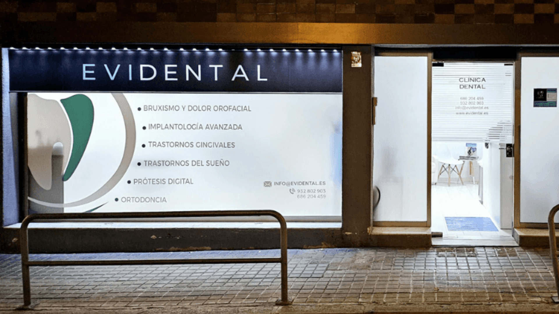 Fachada iluminada de EVIDENTAL, clínica dental en Sarrià (Barcelona), durante la noche.